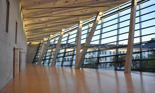 Foyer 3.12 Blick durch das leere Foyer 3.12 bei Sonnenaufgang. Hinter der Wand auf der linken Seite befindet sich der große Saal spectrum. Die Gebäude, die durch die Fenster sichtbar sind, gehören zur Technischen Universität Darmstadt.