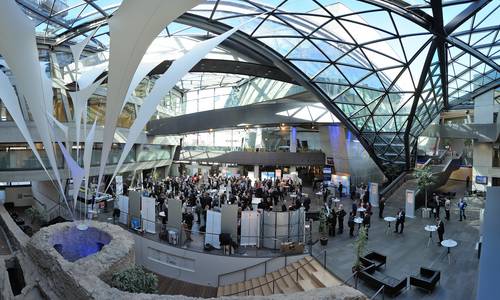 Copyright: Holger Ullmann Im atrium des darmstadtiums sind für eine Veranstaltung Stände aufgebaut, um die sich viele Besucher drängen. Am unteren Bildrand erkennt man die Stadtmauer. Am rechten Bildrand erkennt man die Haupttreppe und die calla.