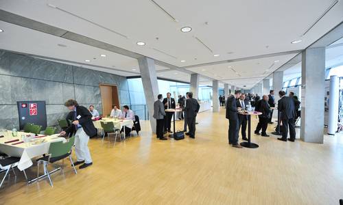 Foyer 3.11 Teilnehmer einer Tagung diskutieren während der Tagungspause im Foyer 3.11. Sie sitzen an Tischen oder stehen an Stehtischen.