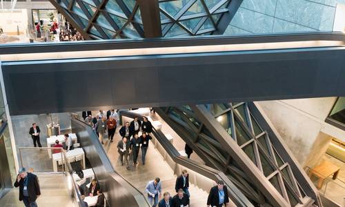 Copyright: DB Netz Dialogforum Fotograf P. von Recklinghausen Seitlicher Blick vom Flur der dritten Ebene hinunter ins atrium. Während einer Veranstaltung laufen viele Gäste die Treppe nach oben. Rechts von der Haupttreppe befindet sich die calla, die vom Dach bis in Tiefgarage des Parkhaus führt.