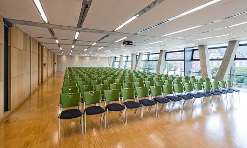 Dreierkombi 2.0234 Blick von der Frontseite des Konferenzraumes titanium3, einer Raumkombination der Räume titanium, vanadium und chromium zu der gegenüberliegenden Wand. Es befinden sich Stuhlreihen im gesamten hell erleuchteten Konferenzraum. Man erkennt das Darmstädter Residenzschloss durch die nicht abgedunkelten Fenster.
