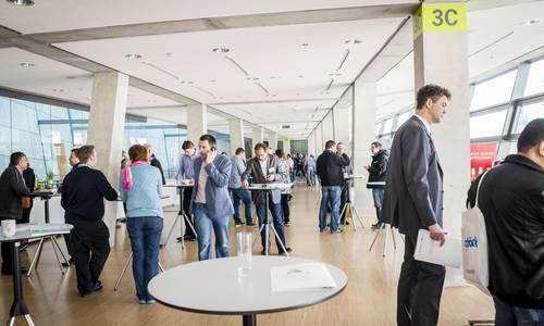 Foyer 3.11 Urheber Fotografie Schepp Blick durch den mittleren Bereich des Foyers 3.11. Im Foyer sind Stehtische aufgebaut, an denen sich viele Teilnehmer während einer Veranstaltungspause aufhalten und sich unterhalten.