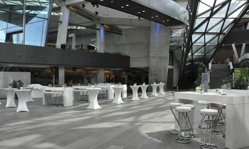 Foyer 0.02 atrium Im atrium sind runde, mit weißen Hussen überzogene Stehtische und weiße, viereckige Stehtische aufgebaut.