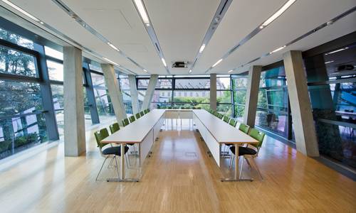 palladium Im lichtdurchfluteten Konferenzraum palladium in der zweiten Ebene ist eine Tischgruppe in U-Form gestellt. Die Tischform ist im Vordergrund offen, im Hintergrund geschlossen. Die Fenster auf der linkem Seite zeigen in Richtung Erich-Ollenhauer-Promenade, die Fenster im Hintergrund in Richtung Schloss.