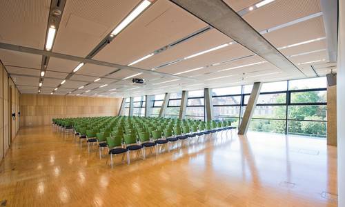 europium Im erleuchteten Konferenzraum europium sind Stuhlreihen aufgebaut. Im Hintergrund befindet sich die Fensterseite mit Blick auf das gegenüberliegende Schloss. Boden und Wände sind aus Bambus.